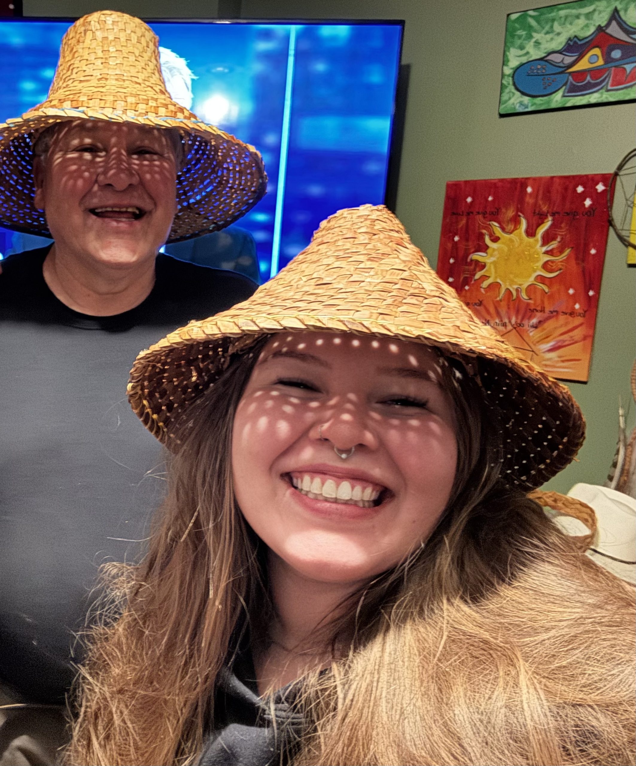 Candidate Ayee Weget-Whitney smiling in a traditional woven cedar hat
